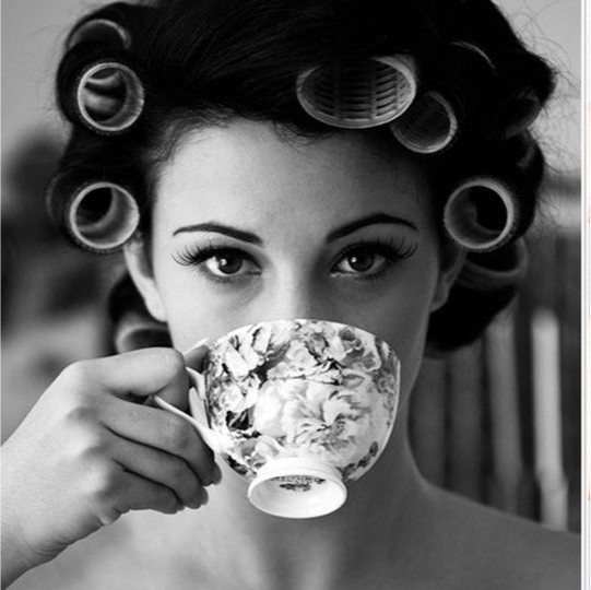 Woman with hair curlers holding a teacup